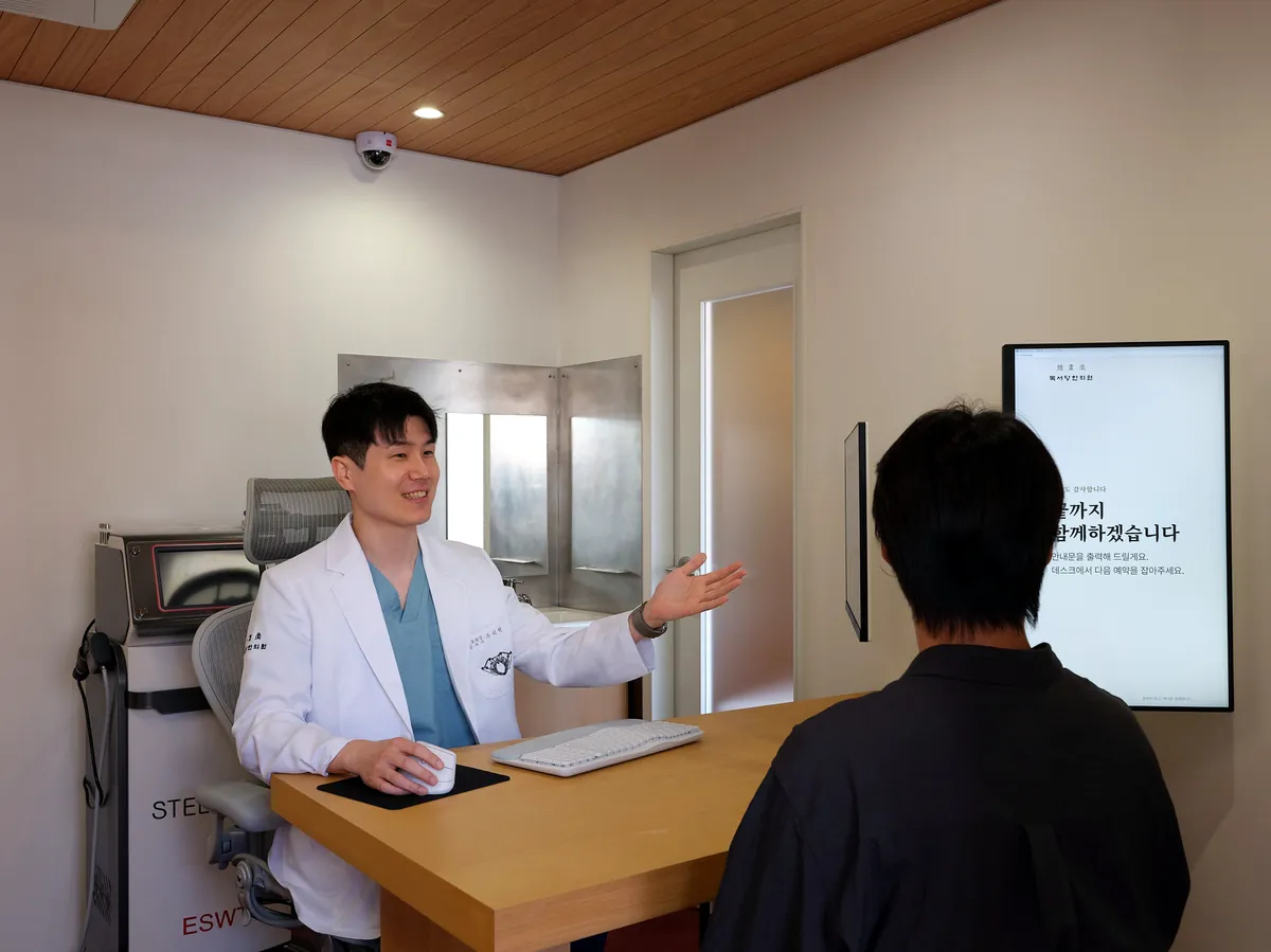 독서당한의원 진료실 상담 — 원장이 화면을 보며 환자에게 설명하는 모습